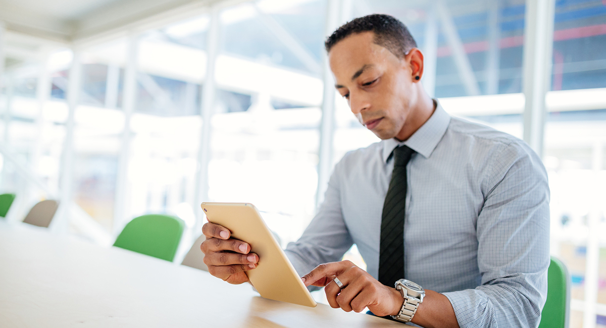Man sitting in office working on a tablet.