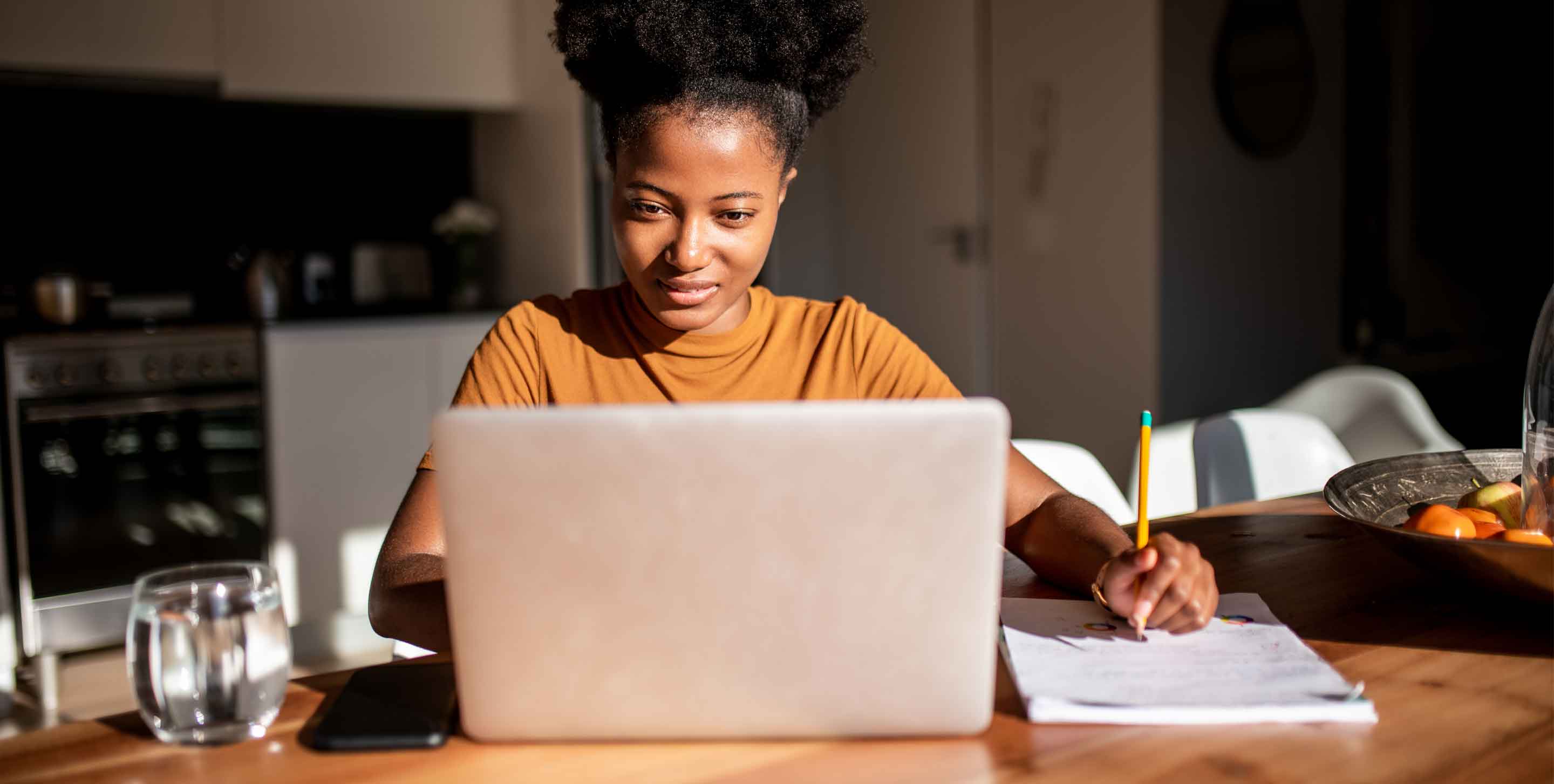 Young woman reading from the computer and taking notes at her notebook