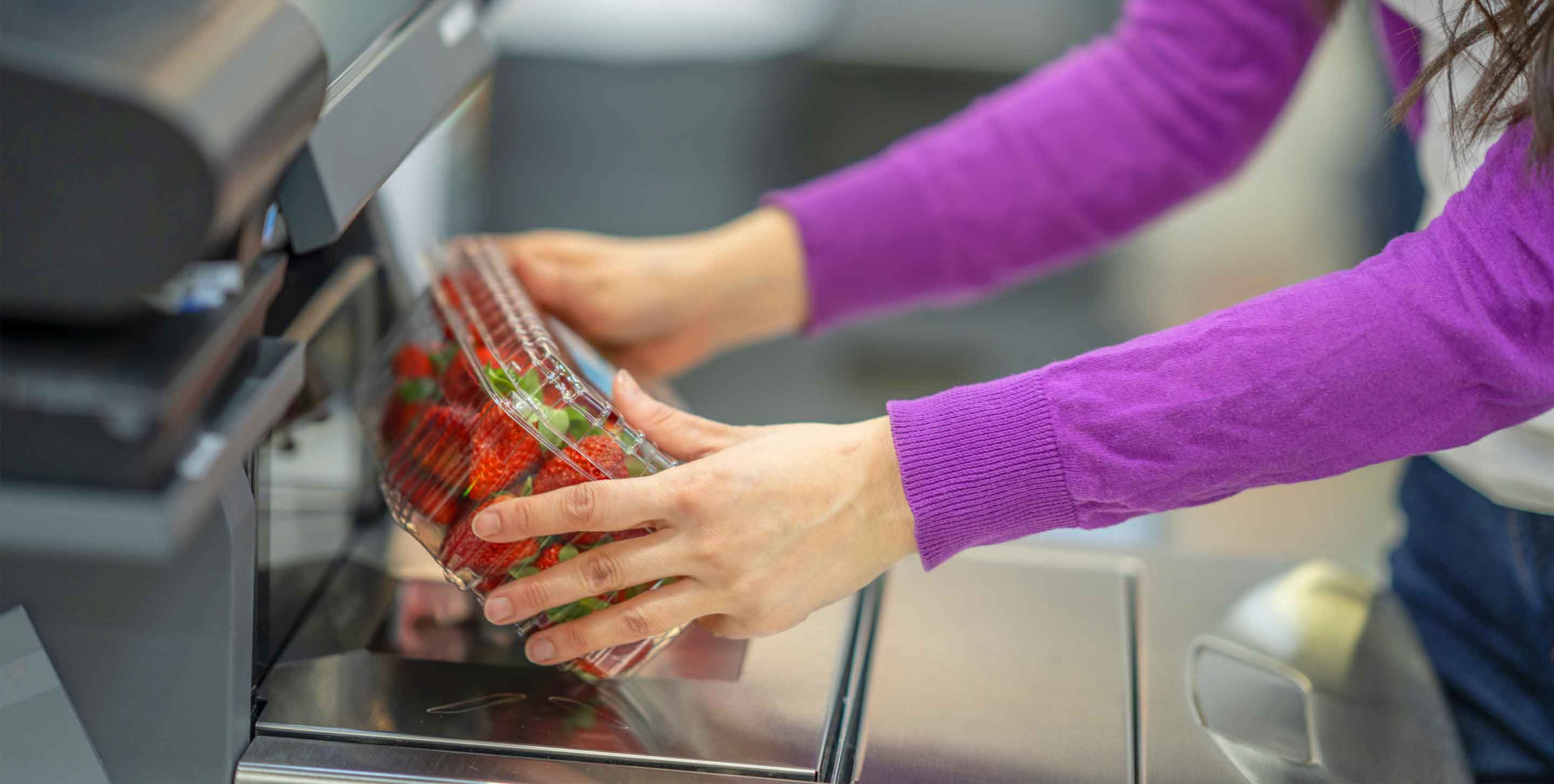 person using self checkout to buy strawberries at a grocery store