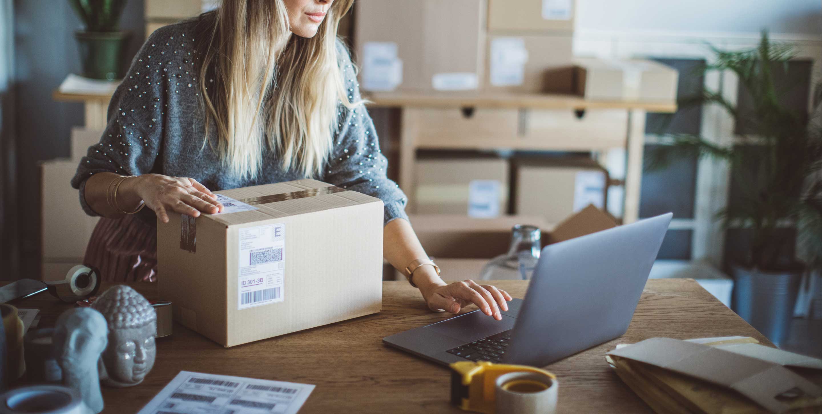 Working woman at online shop. She wearing casual clothing and checking on laptop address of customer and package information