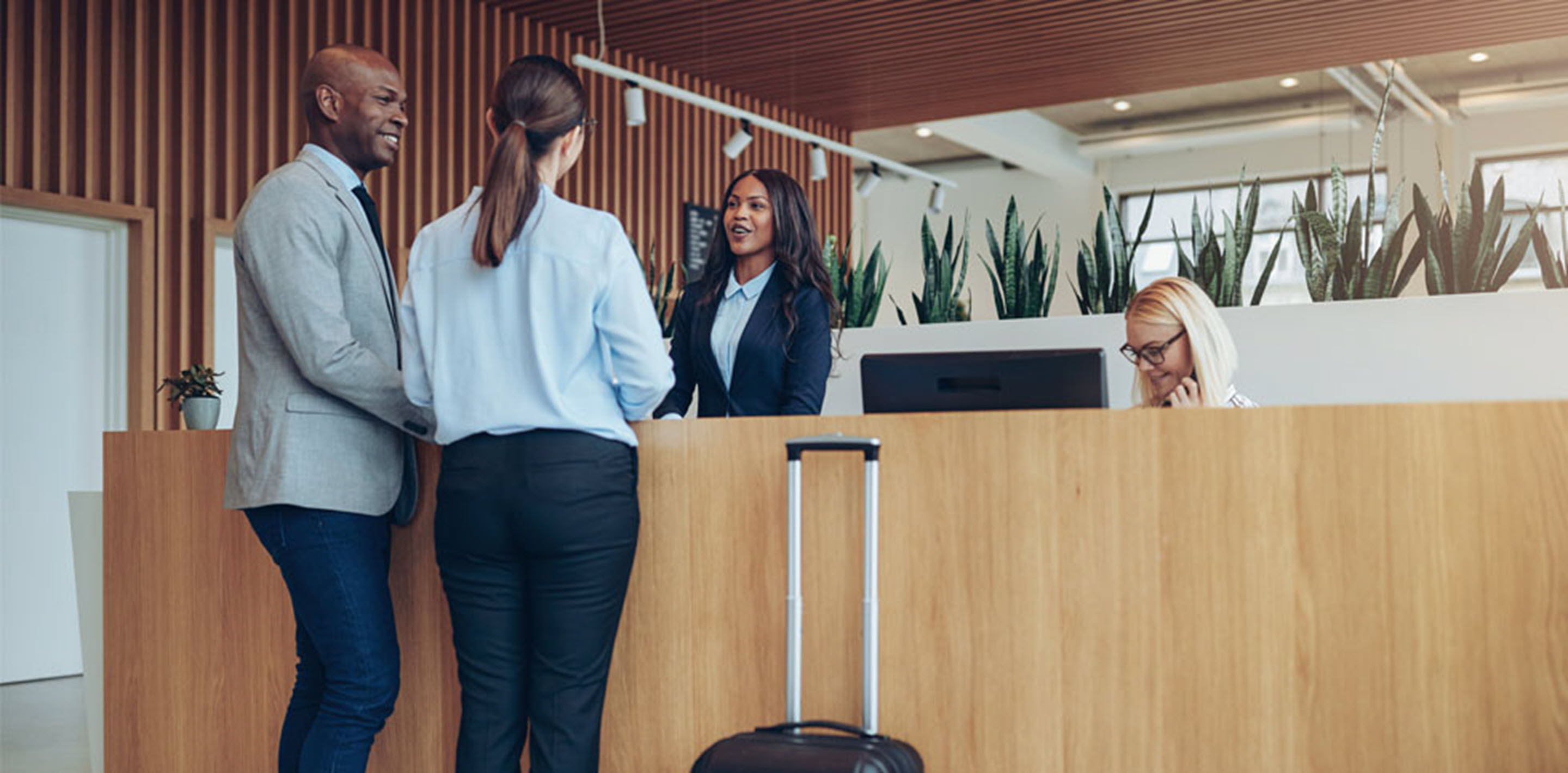 A couple in front of a hospitality service desk, preparing to check in.