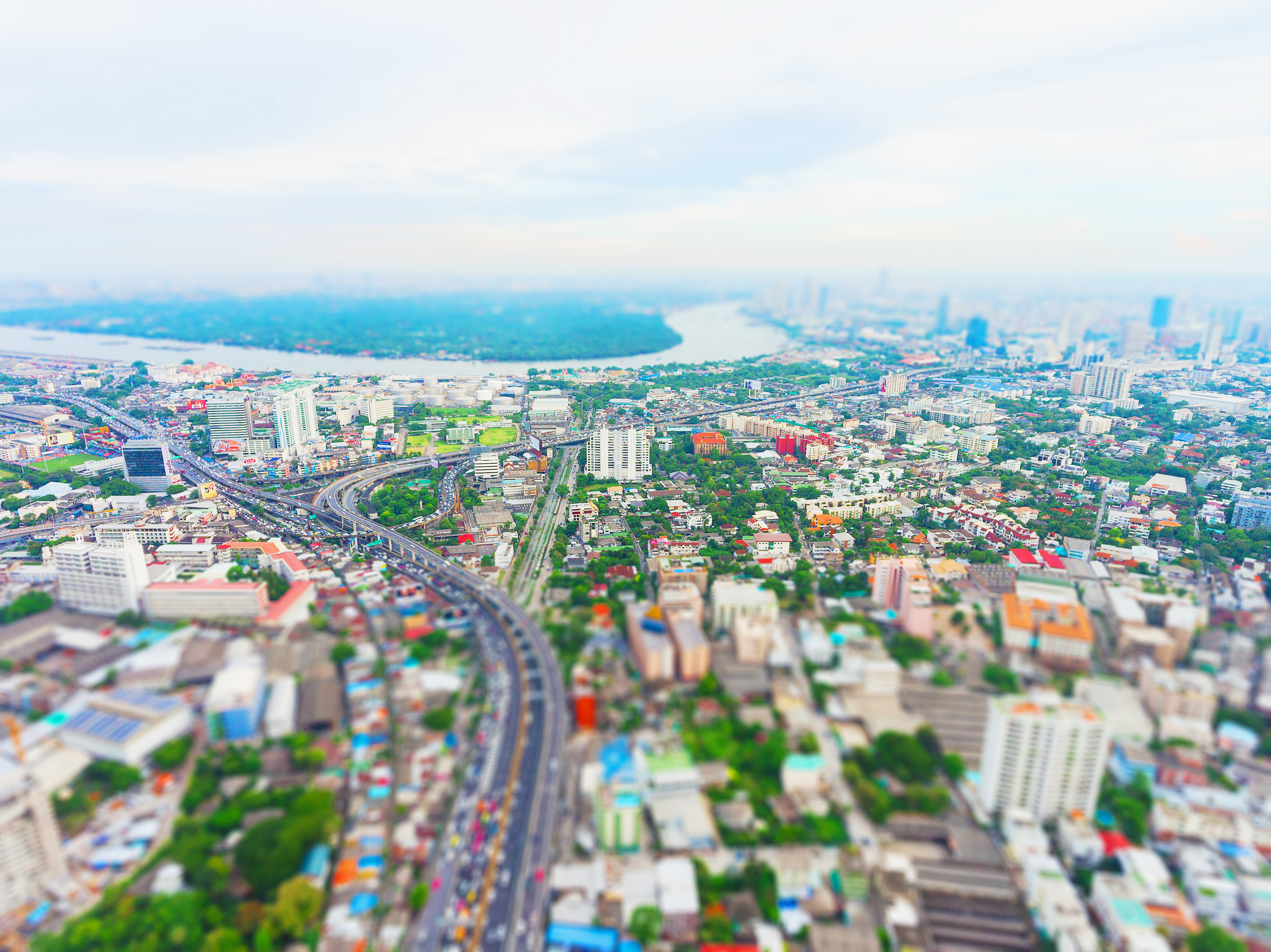 A brightly lit town, edged with greenery and wide roads.