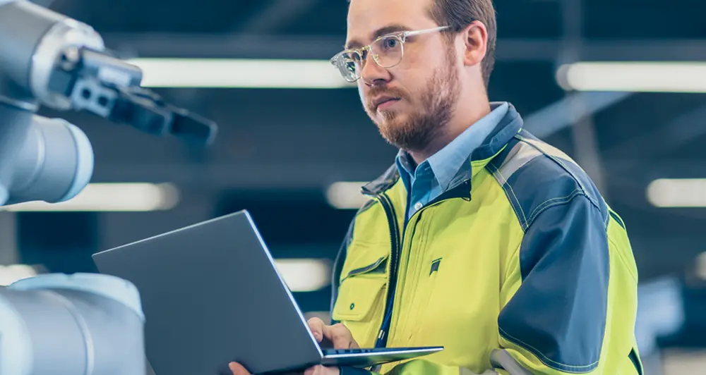 A tech worker reviewing a robotic arm