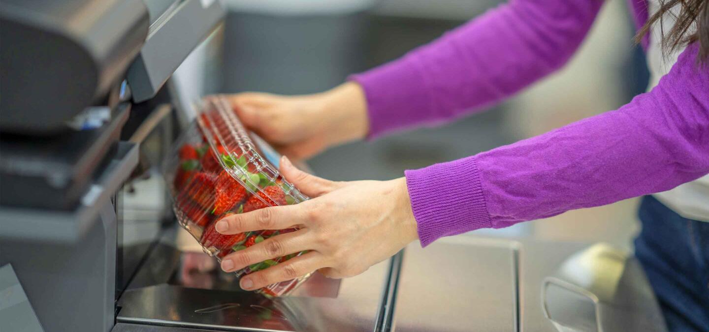 person using self checkout to buy strawberries at a grocery store