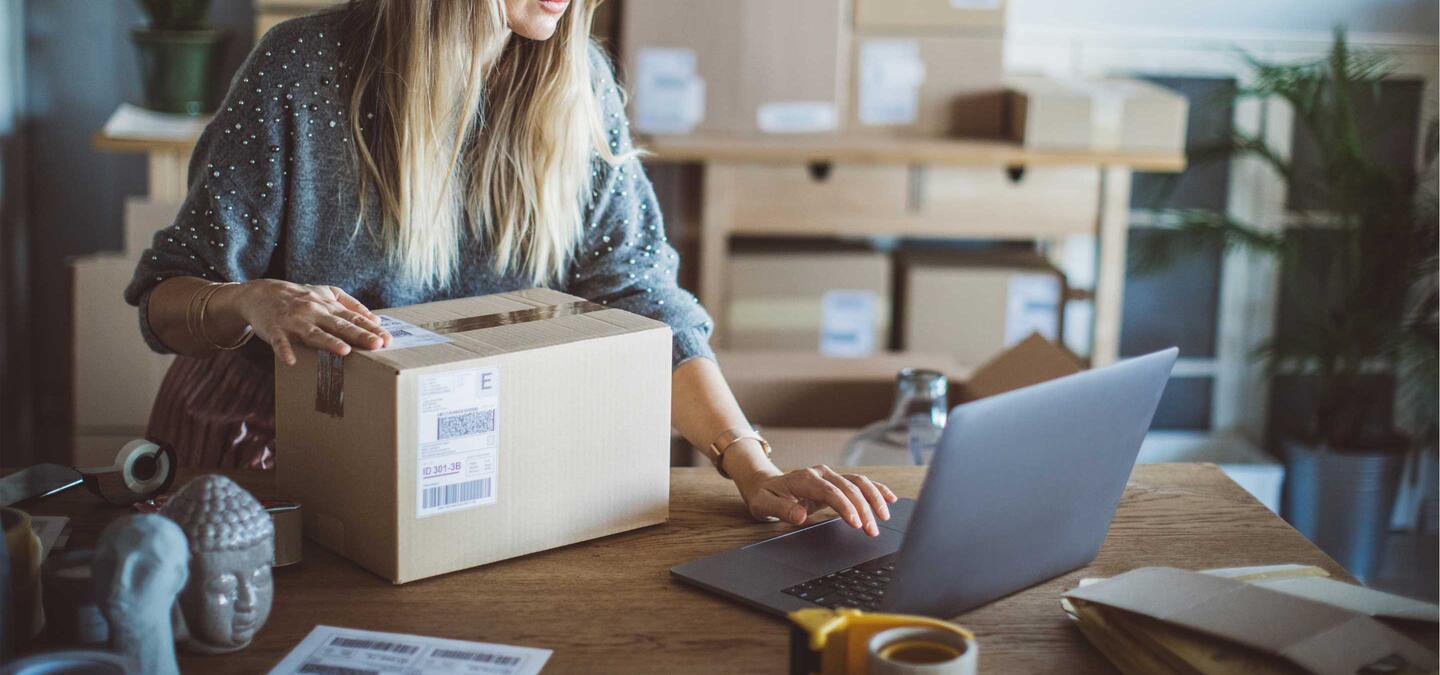 Working woman at online shop. She wearing casual clothing and checking on laptop address of customer and package information