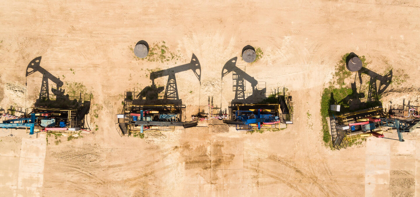 Stylized image of four oil refineries burned into a wooden background