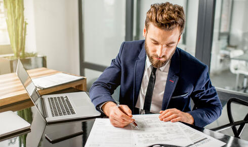 Man in suit reviewing tax calculations on sheet