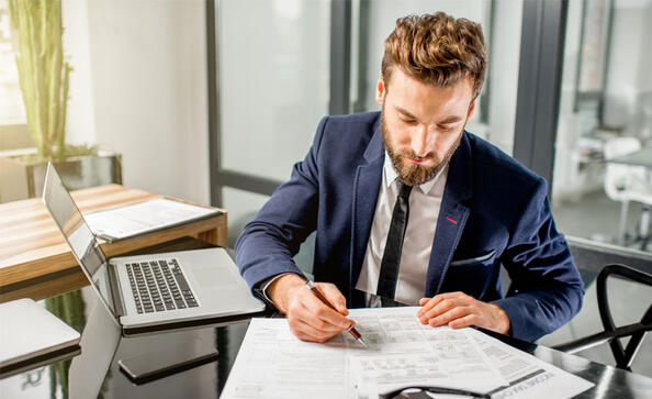 Man in suit reviewing tax calculations on sheet