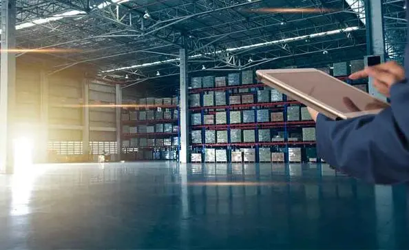 person in a warehouse looking over products on a tablet