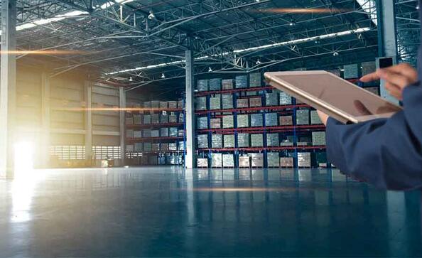person in a warehouse looking over products on a tablet