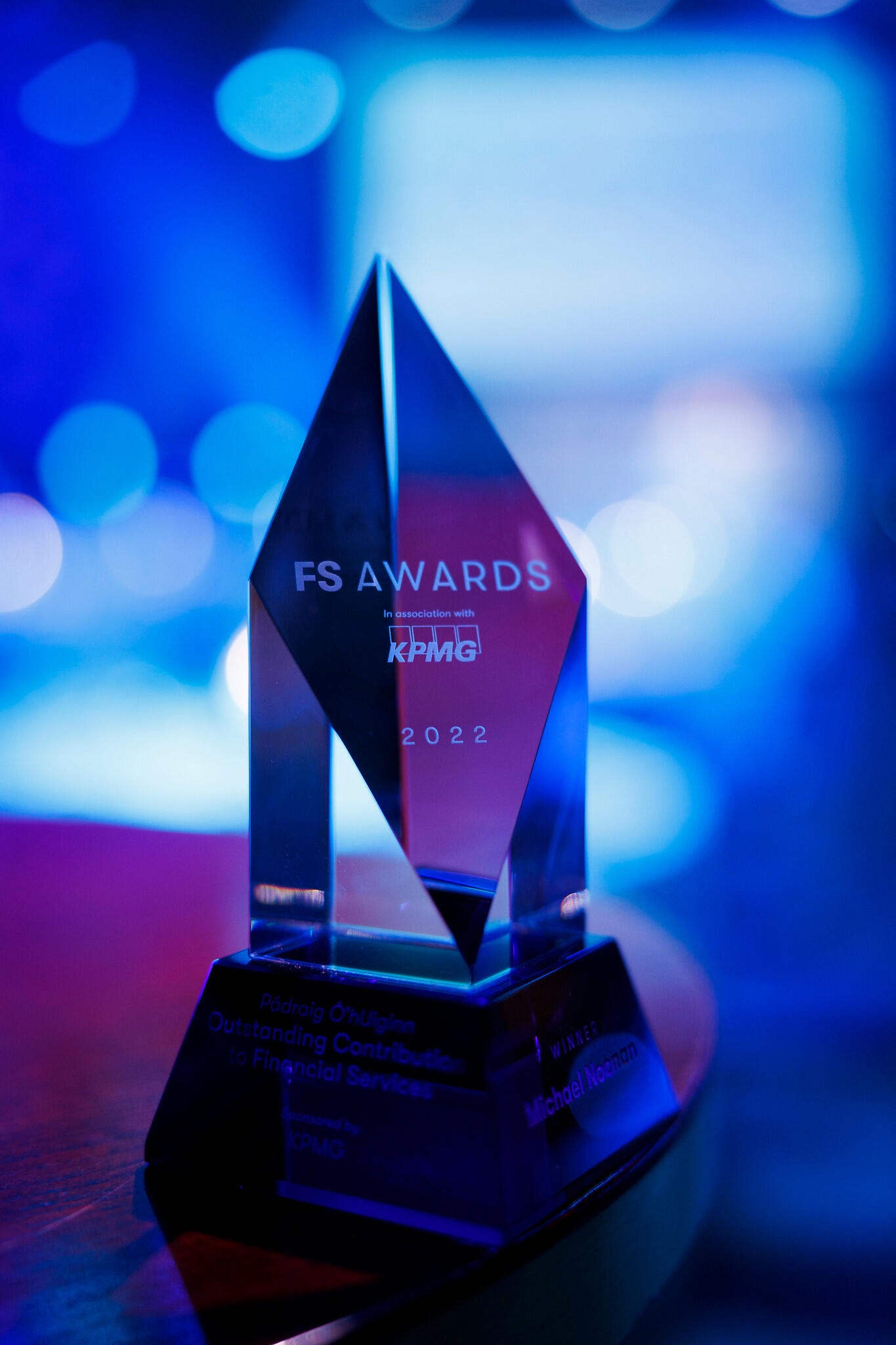 FS Awards trophy for 2022, distributed in association with KPMG. The award is clear and diamond-like, reflecting blue and purple light from the background.